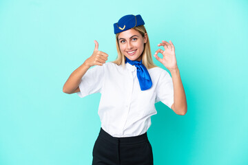 Airplane stewardess Uruguayan woman isolated on blue background showing ok sign and thumb up gesture