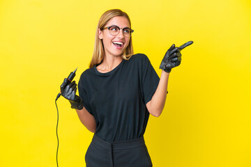 Tattoo artist Uruguayan woman isolated on yellow background pointing finger to the side and...
