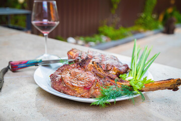 Cooked fried meat with spices on a white plate. Oven-baked meat for dinner with a glass of red wine.