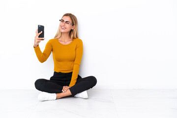 Blonde Uruguayan girl sitting on the floor making a selfie