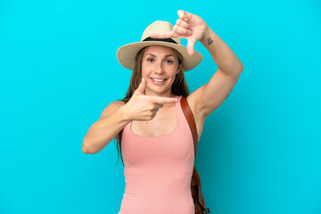 Fototapeta premium Young caucasian woman in summer holidays isolated on blue background focusing face. Framing symbol