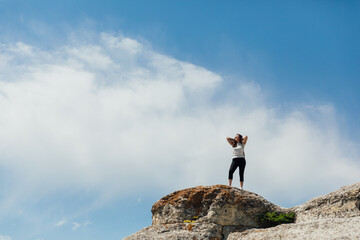 a beautiful woman looks at the view on top of a cliff on a cliff on a journey