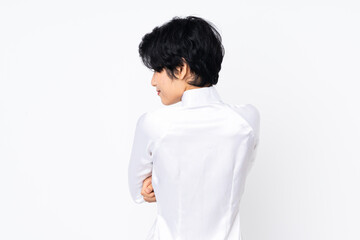 Young Vietnamese woman with short hair wearing a traditional dress over isolated white background in back position