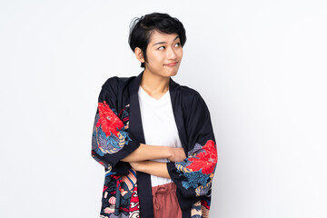 Young Vietnamese woman with short hair wearing a traditional dress over isolated white background making doubts gesture while lifting the shoulders