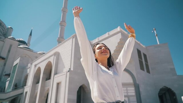 the girl raises her hands to the sky at the mosque