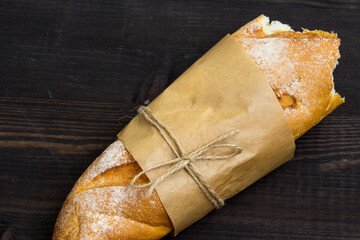Baguette. Fresh golden baguette on an old wooden table. Close-up. French traditional bread on a dark background. Top view. Copy space. - 448643712
