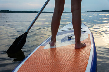 a girl swims on a sup board, beautiful female legs on a sup board with a paddle on a beautiful lake