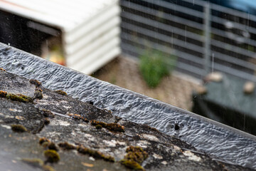 Clogged gutter filled with water that overflows in rainy weather.