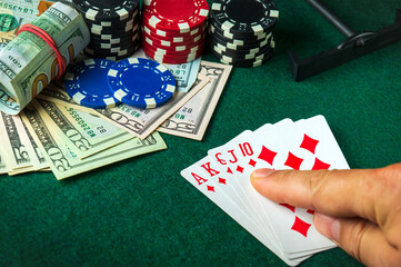 The player points with his finger at a winning Royal Flush combination in a poker game on a table with chips and money in a casino