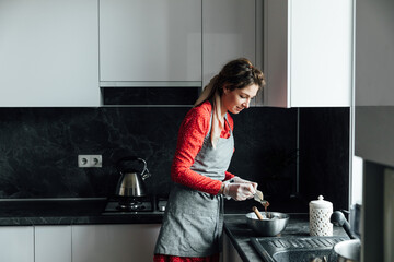 beautiful woman cooks sweet delicious dessert in the kitchen