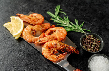 grilled giant prawns on a knife on a stone background