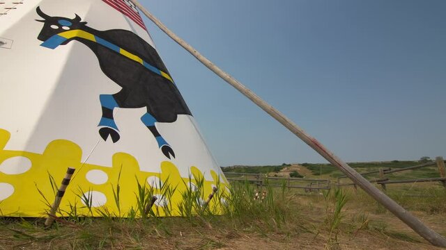 Alberta, Alberta Canada, July 30 2021: Panning motion of a traditional indigenous Teepee standing decorated at the base of Head Smashed in Buffalo Jump.