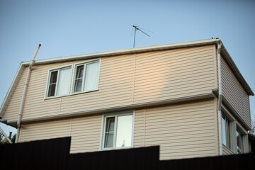 The country house is white. The house behind the fence is far from the city.