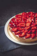 Homemade strawberry pie with syrup on a ceramic platter.