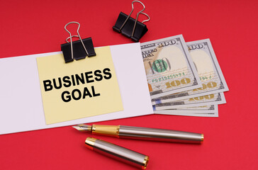 On a red background, an envelope with money and a sticker with the inscription - BUSINESS GOAL