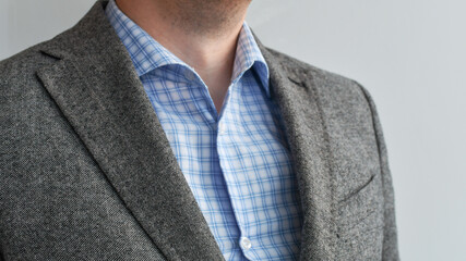 Close up of mens grey wool blazer combined with blue cheked shirt.  Selective focus. Low DOF