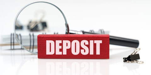 On the table is a notebook, a magnifying glass and a tablet with the inscription - DEPOSIT