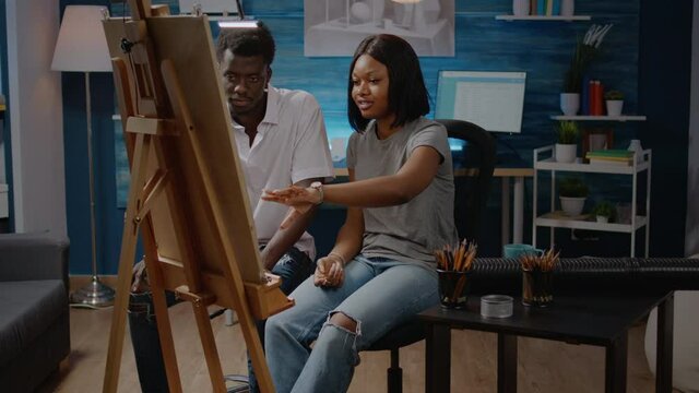African american artists analyzing drawing of vase sitting in artwork studio room at home. Black young man and woman designing modern masterpiece working as team for fine art project