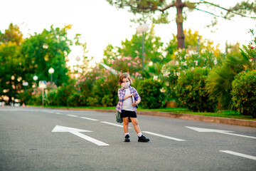 a beautiful little girl, a schoolgirl, is standing on the road, with a backpack, holding a diary in her hands