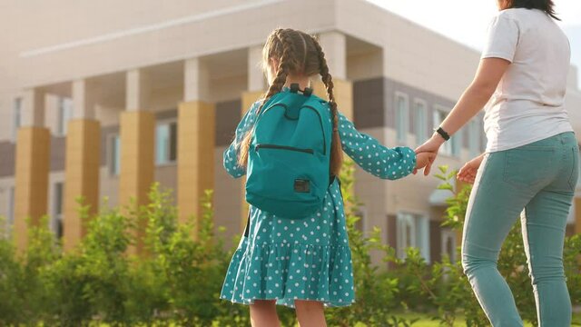 back to school. mom and daughter a go hand in hand to school for lesson. education training sun support concept. child walk to school with a backpack. daughter and mom rush to school. family day