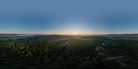 Summer panorama of Ukrainian mountain range. Beautiful summer scenery. Morning fog spreads on the mountain valley. Panoramic summer scene of Carpathian village. Amazing morning landscape of mountain. 