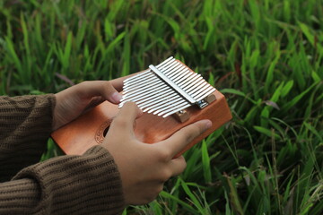 Photo Girl Playing Kalimba, acoustic music instrument from africa 
