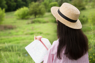 Young beautiful girl reads a book while sitting on a wooden bench in the park. Back view.