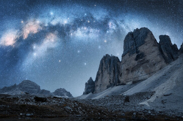 Milky Way arch and mountain peaks at night in summer. Beautiful landscape with blue sky with arched milky way and bright stars, high rocks. Tre Cime in Dolomites, Italy. Space and galaxy. Travel - Powered by Adobe