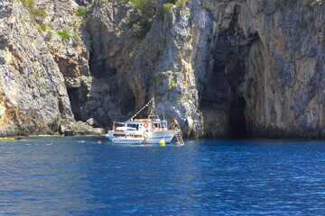 Battello con turisti in tour presso le grotte della costiera del Cilento