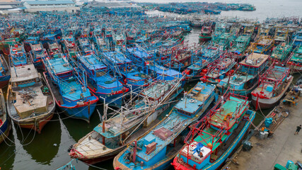 Fototapeta na wymiar Aerial drone view of wooden boats leaning beside the pier. With noise cloud. Jakarta, Indonesia