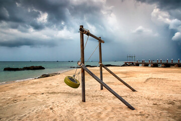 Fototapeta premium a group of clouds and swing in the sand near a body of water