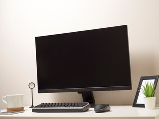 Computer with a wireless keyboard and a wireless mouse on a white table with a black clock a photo frame a mobile phone a white cup of coffee