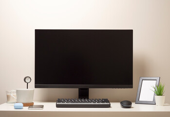 Computer with a wireless keyboard and a wireless mouse on a white table with a black clock a photo frame a mobile phone a white cup of coffee