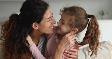 Head shot affectionate young beautiful mother touching noses with smiling little kid daughter. Happy friendly two generations family showing sweet tender feelings, spending time together at home.