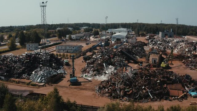 Old wrecked cars in junkyard waiting to be shredded in a recycling park. Aerial view of the car dump with cranes picking up cars