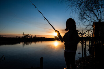 niña disfruta de pesca de invierno en muelle a orillas del rio Paraná con un bello atardecer