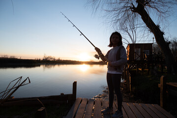 niña disfruta de pesca de invierno en muelle a orillas del rio Paraná con un bello atardecer