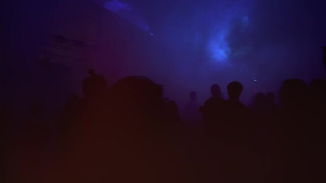 Silhouettes of young youth people on the dance pole dancing at the rave electronic music techno party.