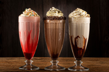 Three glasses of milkshake with assorted flavors. Chocolate, vanilla and strawberry milkshake.