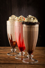 Three glasses of milkshake with assorted flavors. Chocolate, vanilla and strawberry milkshake.