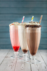 Three glasses of milkshake with assorted flavors. Chocolate, vanilla and strawberry milkshake.
