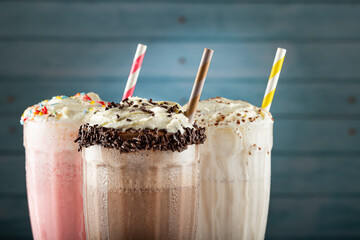 Three glasses of milkshake with assorted flavors. Chocolate, vanilla and strawberry milkshake.