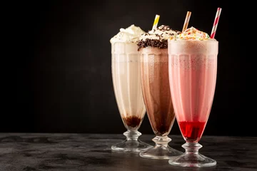 Tuinposter Three glasses of milkshake with assorted flavors. Chocolate, vanilla and strawberry milkshake. © WS Studio