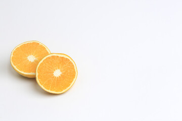 Naranja madura cortada a la mitad situada a la izquierda sobre fondo blanco con espacio para agregar texto. Rodajas de Naranja cortadas a la mitad.