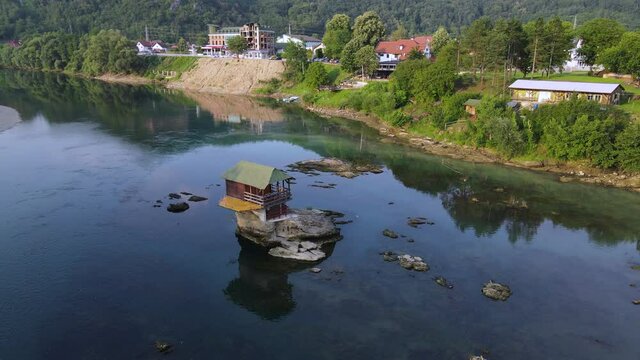 House on Drina River. Serbia. Drone Aerial View of Wooden Cottage on Sunny Day. Tourist Attraction on Rock in the Middle of Water Near Bajina Basta Town