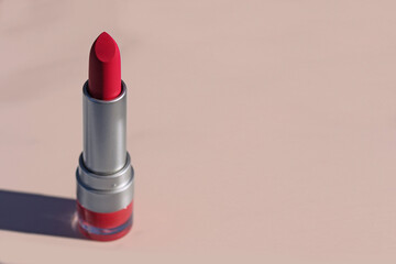 Pink lipstick with a shadow on a pink background. Copy space