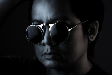 Asian man wearing sunglasses in the dark, black and white photo