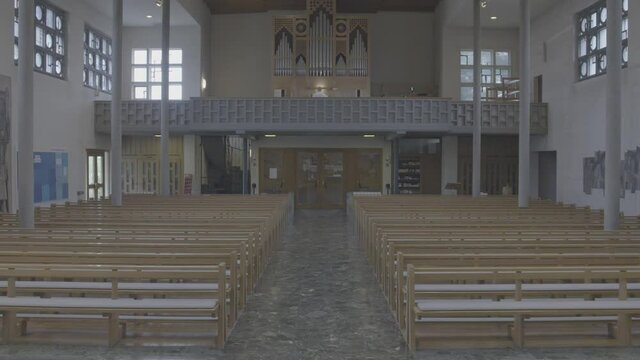 View into the empty church room of the Bruder Klaus church in Gundelfingen, Germany, a man is playing the organ