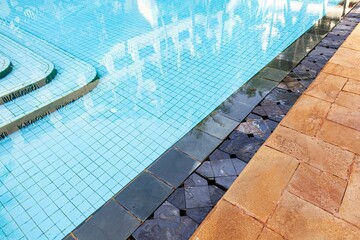 Wide swimming pool and brown stone floor inside the villa