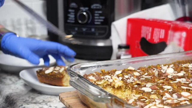 Taking A Piece Of Sliced Banana Cake From Pyrex Glass Dish And Place It On Plate with Blue Rubber Gloves - Closeup Shot